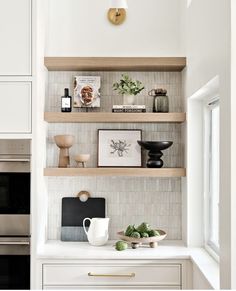 a kitchen with white cabinets and wooden shelves