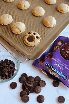 cookies and chocolate chips on a cookie sheet next to a baking pan with half - eaten cookies