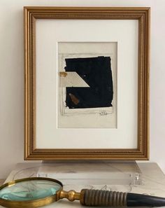 a framed painting with a magnifying glass next to it