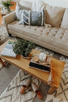 a living room with a couch, coffee table and books on the floor in front of it