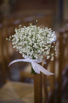 a bouquet of baby's breath in a vase on a chair at a wedding