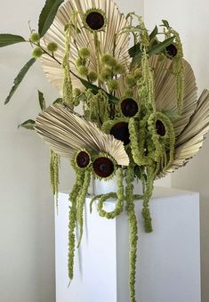 an arrangement of flowers is displayed on a pedestal