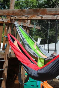 a person laying in a hammock on a wooden structure with other items nearby