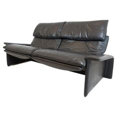 a black leather couch sitting on top of a white floor