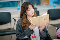 a woman sitting at a table reading a book