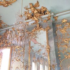 ornate gold mirrors and chandeliers in a room with light blue walls, white ceiling