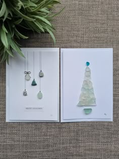 two cards with christmas trees on them next to a potted plant