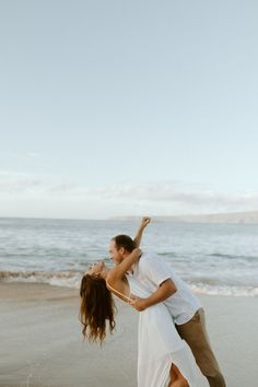 a man and woman dancing on the beach