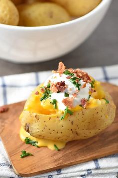 baked potato casserole with bacon and sour cream in a white bowl on a wooden cutting board