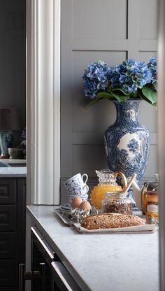 a blue and white vase sitting on top of a counter next to a tray filled with food