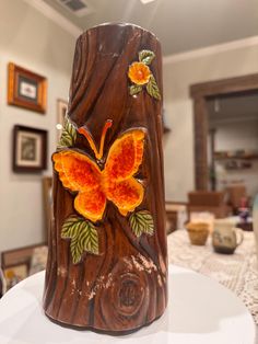 a wooden vase with an orange butterfly painted on the side sitting on top of a table