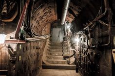 an underground tunnel with stairs leading up to the ceiling and lights on either side of it