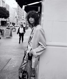 a woman leaning against a wall on the sidewalk