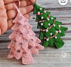 two small christmas trees are being held by someone's hand with buttons on them