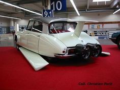 an old car is on display in a building with red carpet and white walls, along with other antique cars