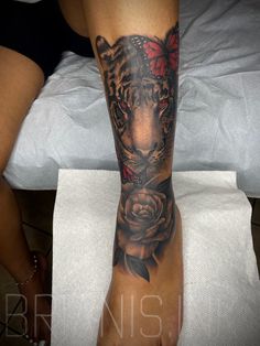 a woman's leg with a tiger and rose tattoo on it