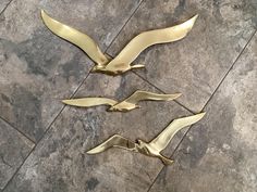 three metal birds sitting on top of a tile floor