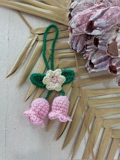 two crocheted bells hanging from a palm leaf on a wall next to flowers