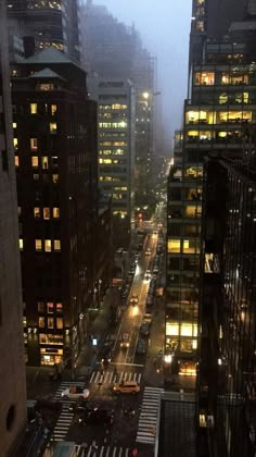 a city street filled with lots of traffic next to tall buildings in the foggy night