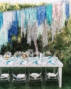 a long table with chairs and plates on it in the middle of some grass covered ground