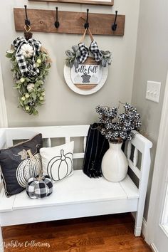 the entryway is decorated for fall with wreaths and pumpkins on the bench