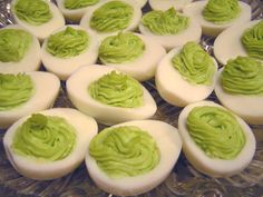 an assortment of deviled eggs with green toppings on a glass platter, ready to be eaten