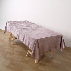 a table with a pink cloth on it in front of a white wall and wooden floor