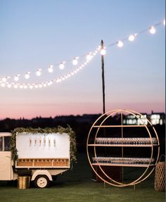 two food trucks parked next to each other on top of a grass covered field at night