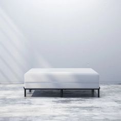 a white bed sitting in the middle of a room next to a wall with light coming through it