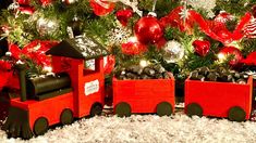 a christmas tree decorated with red and silver ornaments, train ornament and other holiday decorations