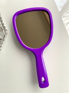 a purple mirror sitting on top of a white table