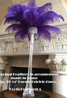 a tall vase filled with purple feathers on top of a table