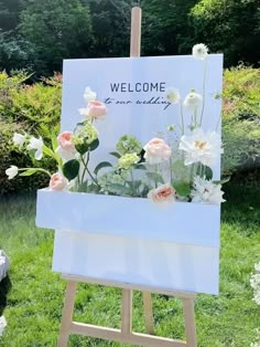 a welcome sign with flowers on it in the grass