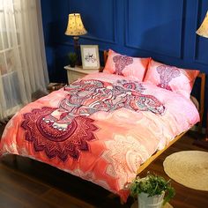 a bed with an elephant design on the comforter and pillows in front of a blue wall