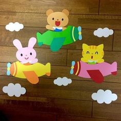 some paper cut out of animals and planes on a wooden floor with clouds in the background