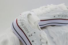 a pair of white sneakers with pearls on them