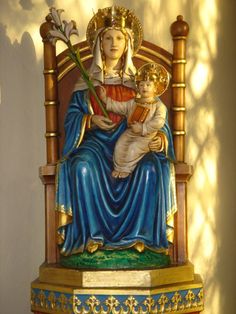 a statue of the virgin mary and child jesus on a chair with gold trimmings