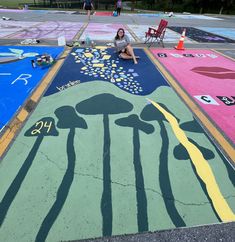 a woman sitting on the ground in front of some chalk art