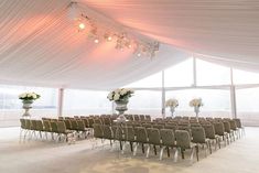 the inside of a large tent with rows of chairs and vases on each side