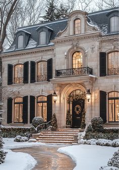 a large white house with black shutters in the snow