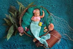 a baby doll is laying in a basket on the floor next to plants and other items