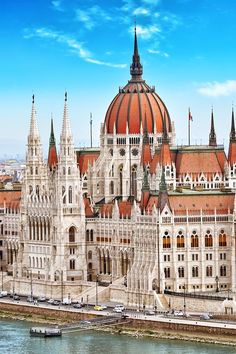 the hungarian parliament building in budapest, with a boat passing by on the river bank