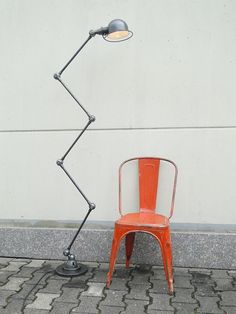 an orange chair sitting in front of a lamp on the side of a building next to a sidewalk