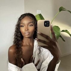 a woman taking a selfie in front of a plant with her cell phone up to her ear