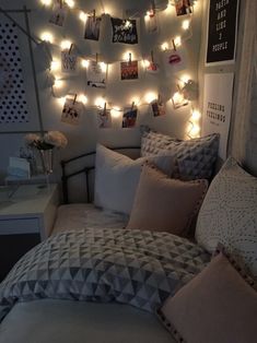 a bedroom with lights strung over the headboard and pillows on the bedspread