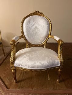 an ornately decorated chair sitting on top of a wooden floor next to a mirror