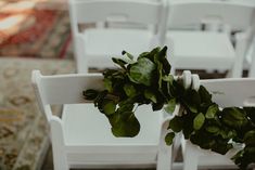 white chairs are lined up with green plants on them