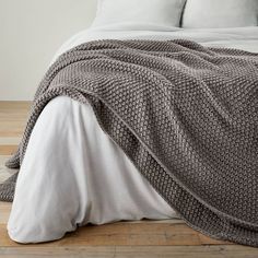 a bed covered in a gray blanket and pillows