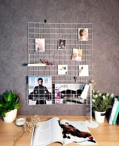 an open book sitting on top of a wooden table next to a plant and pictures