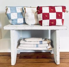 three bags sitting on top of a wooden table next to a pile of folded towels